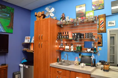 An image of a shelf filled with hair products, collectables, and a cabinet for barber's tools.