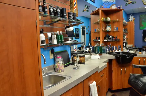 An image of a shelf filled with hair products, collectables, and one of the counters in the barbershop.